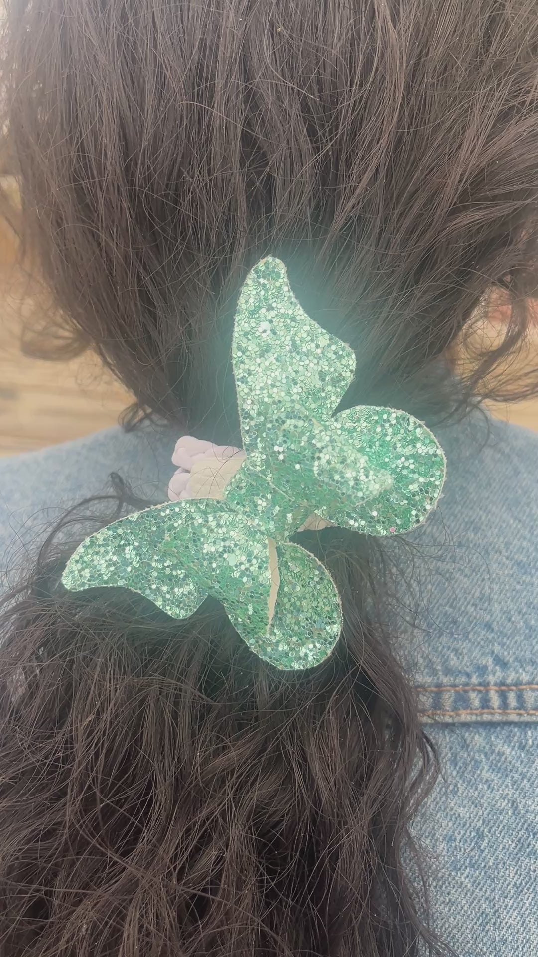 Load video: Gather the hair together. Wrap the hair tie around the hair. If the center magnet faces inward than turn it outward. Connect the Chic Hairbow to the Chic Hairband.
